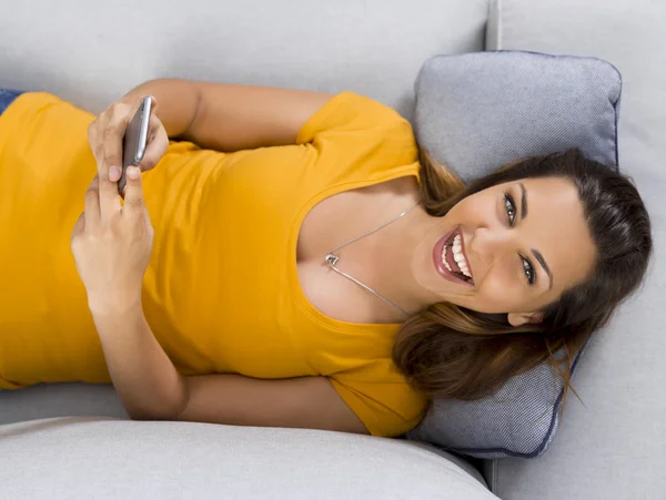 Kobieta w żółty T-shirt, leżąc na kanapie — Zdjęcie stockowe