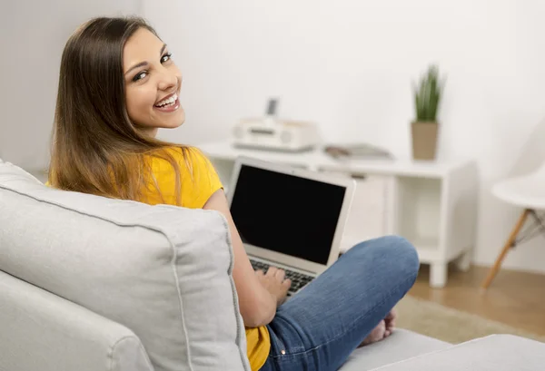 Kvinna i gul T-shirt som sitter på soffan — Stockfoto