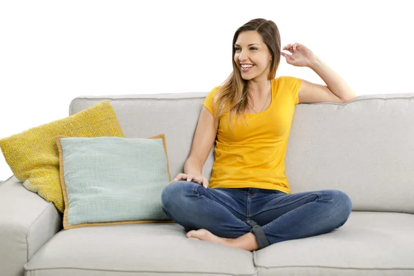 Žena v žluté tričko sedí na pohovce — Stock fotografie