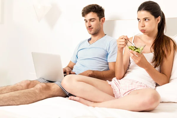 man looking laptop while woman eating