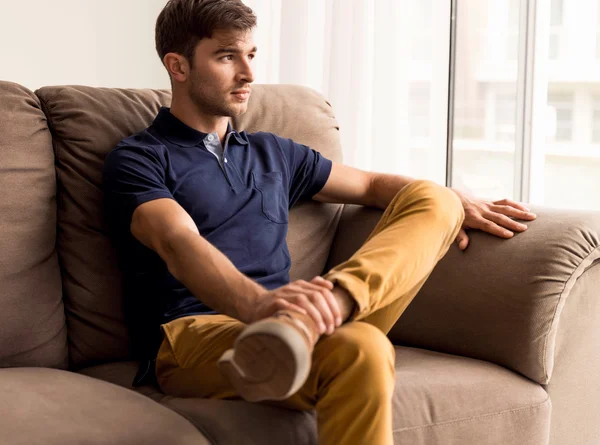 Jeune homme assis sur le canapé — Photo