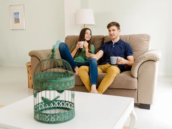 Pareja bebiendo café mientras ve la televisión — Foto de Stock