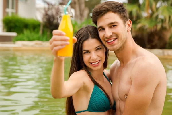 Paar umarmt sich im Pool mit Saft — Stockfoto