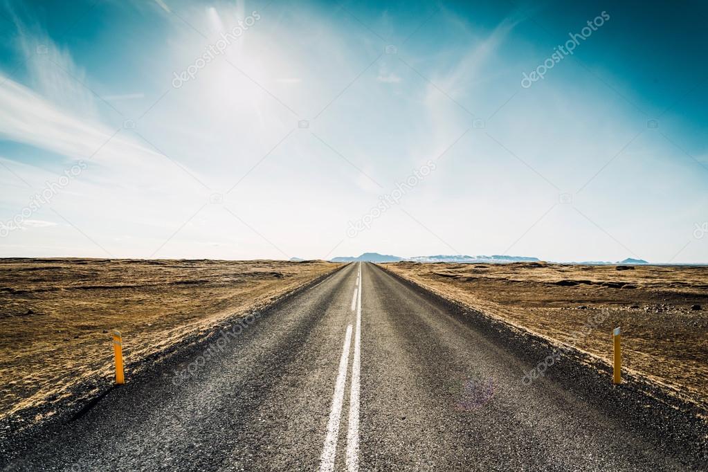 Endless asphalt road between meadow