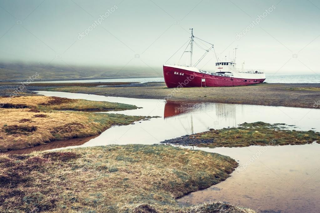 red ship standing on sand in coast