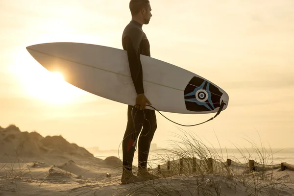 Surfista de pie con tabla de surf en las dunas — Foto de Stock