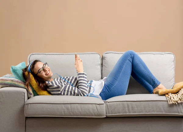 Жінка на дивані слухає музику — стокове фото
