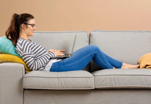 Mulher no sofá trabalhando com laptop — Fotografia de Stock