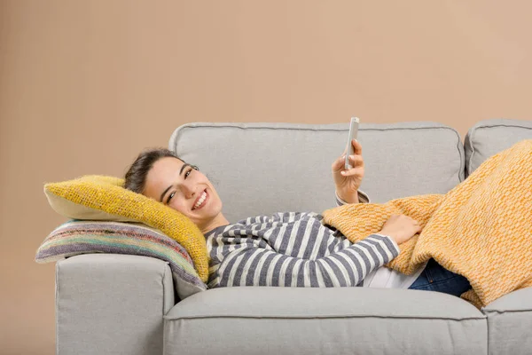 Γυναίκα στον καναπέ χρησιμοποιώντας το τηλέφωνο — Φωτογραφία Αρχείου