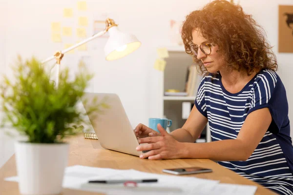 Жінка в офісі працює з ноутбуком — стокове фото
