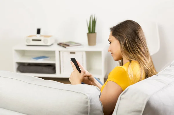 Mujer sentada en un sofá con smartphone —  Fotos de Stock