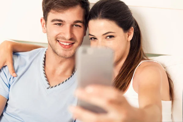 Ouple na cama fazendo selfies — Fotografia de Stock