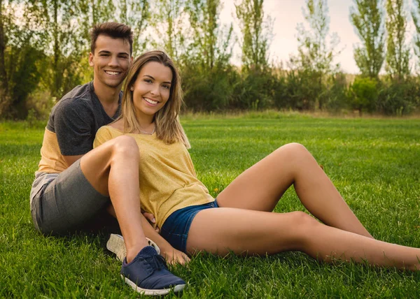 Jeune couple assis sur l'herbe — Photo