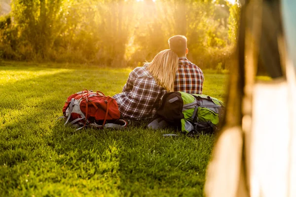 Echtpaar met rugzakken zittend op het gras — Stockfoto