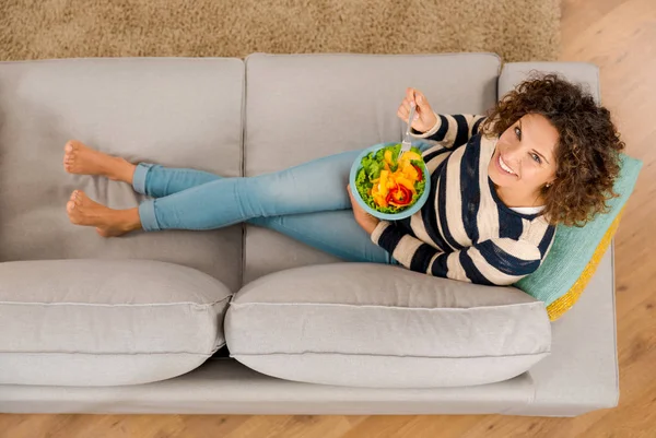 Femme avec salade sur canapé — Photo