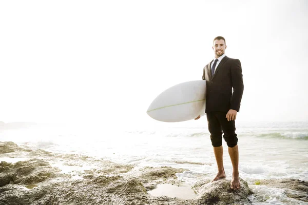 Affärsman innehav surfbräda på stranden — Stockfoto
