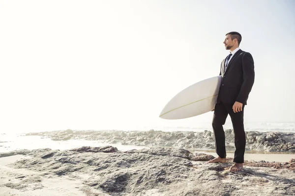 Geschäftsmann hält Surfbrett am Strand — Stockfoto