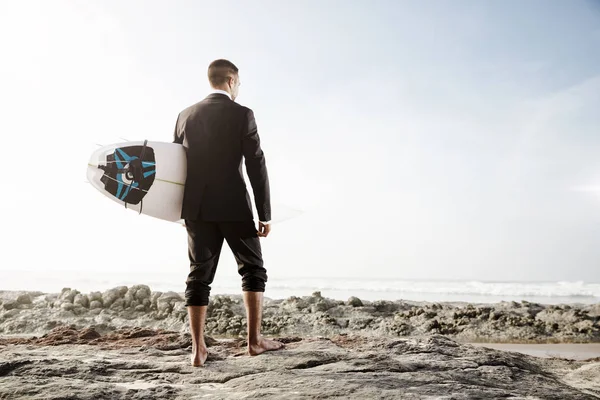 Geschäftsmann hält Surfbrett am Strand — Stockfoto