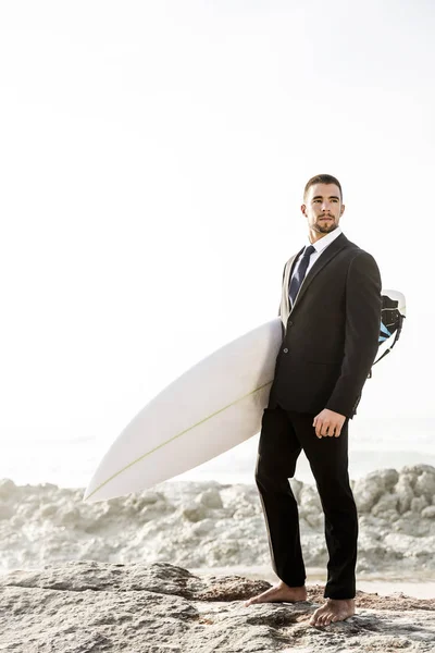 Geschäftsmann hält Surfbrett am Strand — Stockfoto