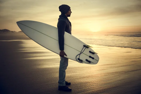 Серфер с доской для серфинга на закате — стоковое фото