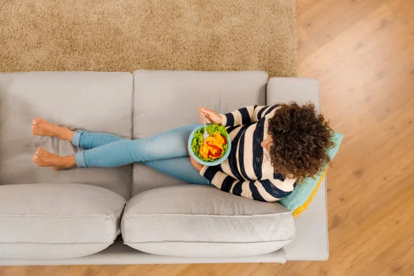 Mulher no sofá comendo salada — Fotografia de Stock