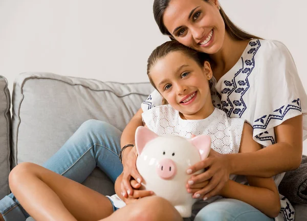 Mãe e filha com um banco porquinho — Fotografia de Stock