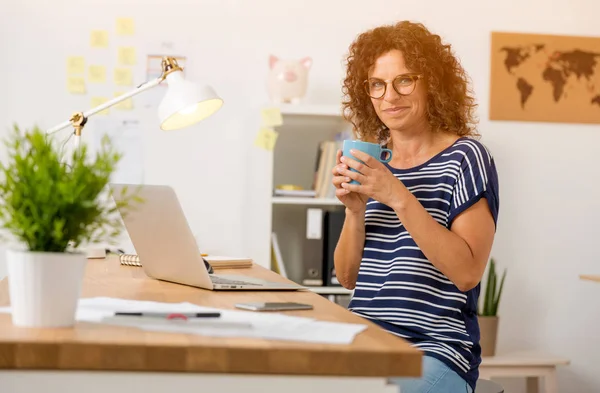 Mulher bebendo café quente no escritório — Fotografia de Stock