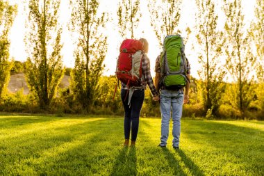 çayır üzerinde sırt çantaları ile genç Çift