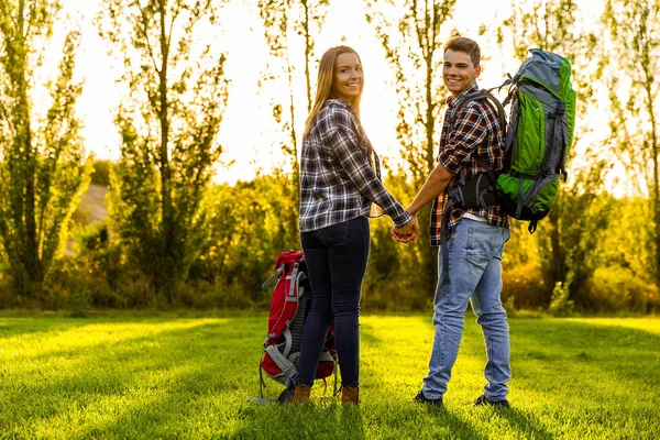 Jong koppel met rugzakken op weide — Stockfoto