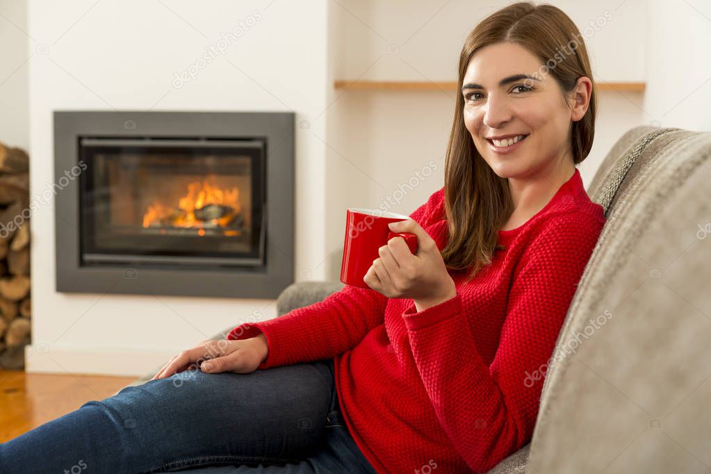 Woman drinking coffee at fireplace