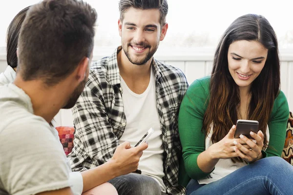 Vänner som sitter på soffan med telefoner — Stockfoto