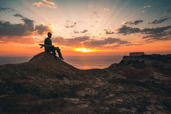 Hombre con tabla de skate al atardecer —  Fotos de Stock