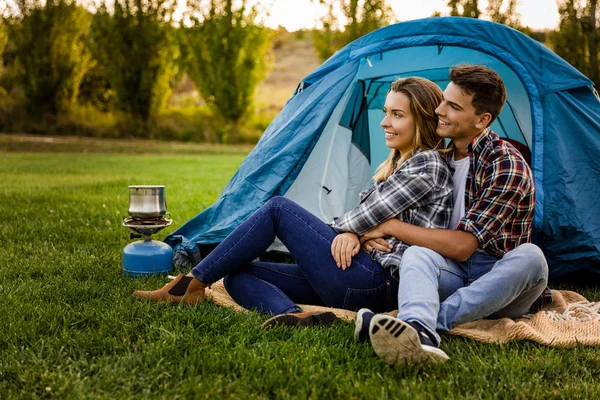 Casal abraçando sentado no acampamento — Fotografia de Stock