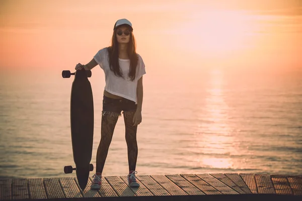 Молода жінка позує зі скейтбордом — стокове фото