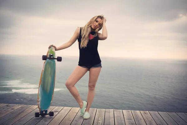 Молодая женщина позирует со скейтбордом — стоковое фото