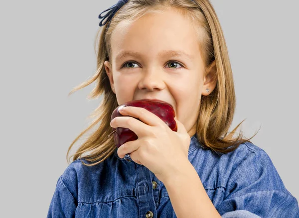 Милая девушка ест красное яблоко — стоковое фото