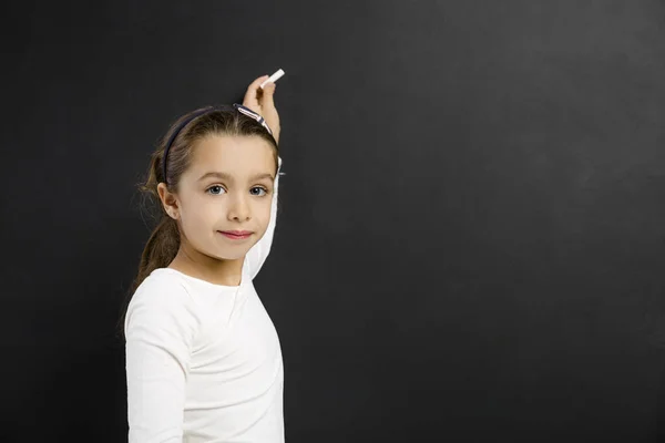 Girl writing on a blackboard — Stock Photo, Image