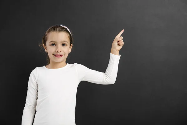 Little girl pointing to a blackboard — Stock Photo, Image