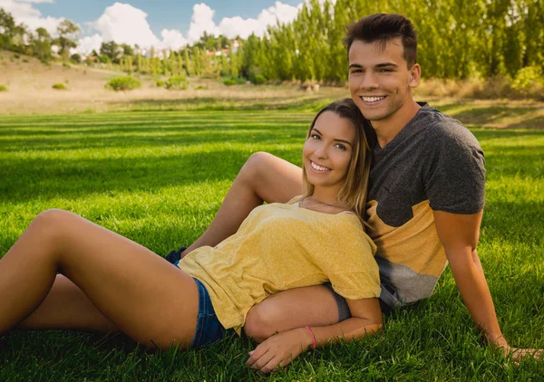 Çimlerde oturan genç bir çift — Stok fotoğraf