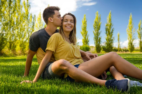 Młoda para siedzi na trawie — Zdjęcie stockowe