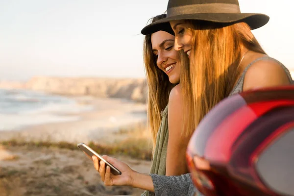 Två Kvinnliga Vänner Leende Med Telefon Stranden — Stockfoto