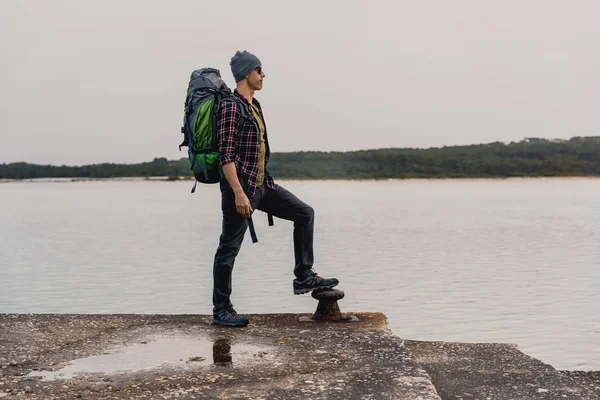 Człowiek Plecaka Stojąc Brzegu Cieszyć Się Piękny Widok Jezioro Pochmurny — Zdjęcie stockowe