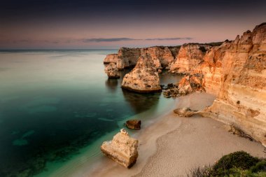 Sandy beach kayalıklarla gün batımında, Marinha Beach, Portekiz ile