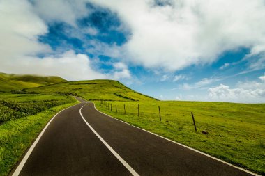 Empty road with green fields by sides in Flores Island, Azores, Portugal clipart