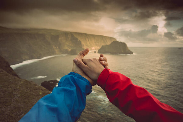 Woman and man holding hands against scenic marine landscape