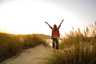 kadın kumsalda gün batımında kaldırdı kollarını
