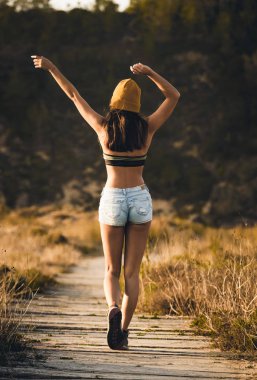 Arkadan görünüş genç kadın tarafından ahşap yolu yürüyüş