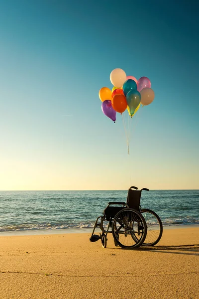 色の風船とビーチで車椅子 — ストック写真
