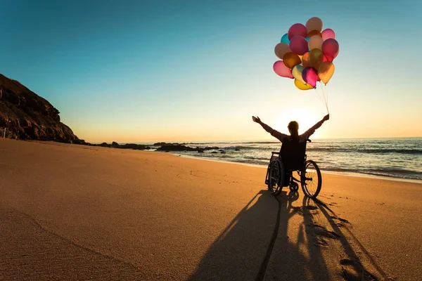 Homem Deficiente Cadeira Rodas Com Mãos Levantadas Balões Coloridos Praia — Fotografia de Stock