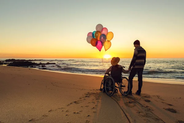 Kadın Balonlar Tutarak Erkek Arkadaşıyla Yürüyüş Tekerlekli Sandalye Üzerinde — Stok fotoğraf